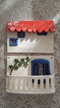 two plastic plates with red and blue roofing on top of each other in front of a lace tablecloth