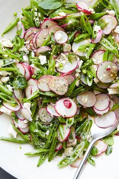 a white plate topped with radishes and other veggies next to a fork