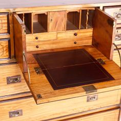 an old wooden desk with drawers and a leather pad in the bottom drawer that is open