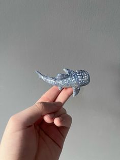 a hand holding a small toy alligator in it's right hand and the other hand is pointing at it