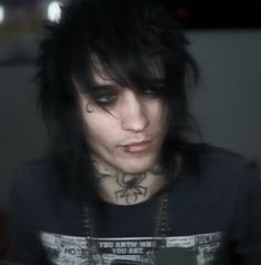 a man with black hair and piercings on his face looking at a cell phone