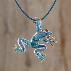 A spry sky blue glass frog with red and orange accents handblown with a pipette and with torch worked details hangs from a blue waxed cotton cord in this pendant necklace. Handcrafted by Costa Rican artisan Guisselle Mora the frog has tiny air bubbles captured in the glass characteristic of handblown glass. A sliding knot in the cord allows the necklace length to easily be adjusted. Unique Glass Necklace Pendant Folksy, Cheap Unique Glass Necklaces, Fire Glass Necklace, Glass Jewelry Pendant, Fused Glass Keychains Animal, Red Eyed Frog, Glass Frogs, Handblown Glass Pendant, Frog Stuff