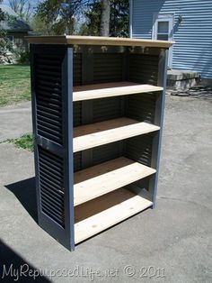 an empty bookcase sitting on the side of a road in front of a blue building