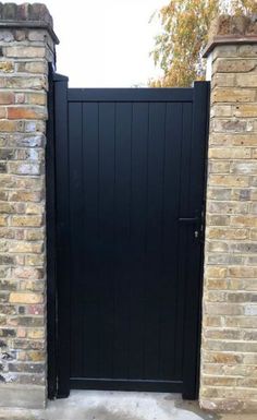 a black gate is open on the side of a brick building