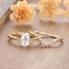 two wedding rings with pearls on them sitting next to each other in front of flowers