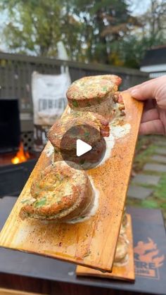 someone is holding up some food on a wooden board