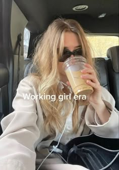 a woman sitting in the back seat of a car drinking from a cup with headphones on