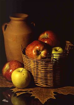 apples in a basket next to a vase on a table