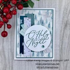 a close up of a christmas card on a table with berries and pine cones in the background