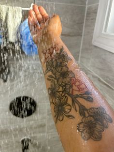 a person's arm with flowers on it in the shower