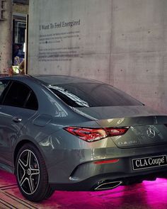 a car parked in front of a building with purple lights on the side of it