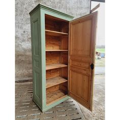 an open wooden cabinet sitting on top of a cement floor next to a wall and door