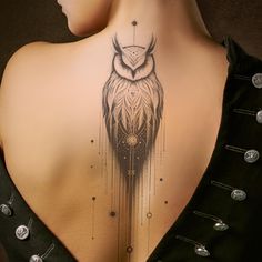 an owl tattoo on the back of a woman