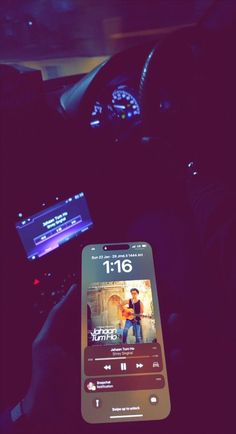 a cell phone sitting in the middle of a car with music playing on it's screen