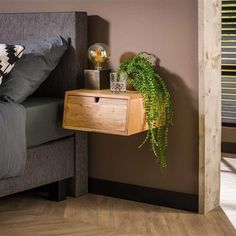 a bed with a plant on the nightstand next to it