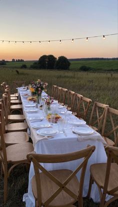 a long table is set with plates and glasses for dinner in the middle of an open field