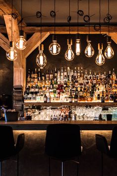 a bar with lots of bottles and lights hanging from the ceiling