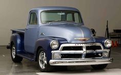 an old blue truck parked in a garage