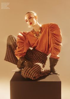 a woman sitting on top of a black box with her legs crossed in the air