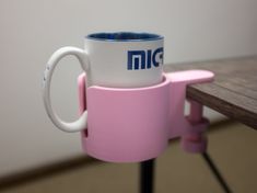 a pink coffee cup sitting on top of a wooden table