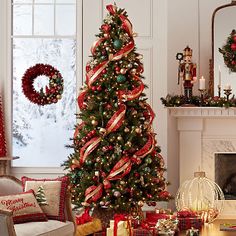 a decorated christmas tree sitting in front of a fire place next to a fireplace with presents on it