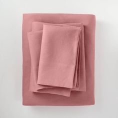 three folded sheets on top of each other in different colors and sizes, one pink