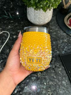 a person holding a yellow yeti cup in their hand on a granite counter top