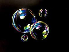 three soap bubbles floating in the air on a black background