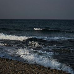 the waves are crashing on the beach at night