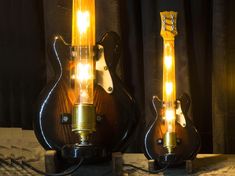 two electric guitars are sitting side by side on a table, one is turned yellow and the other is black