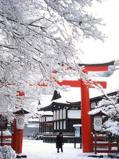 a person standing in front of a red and white building with snow on the ground