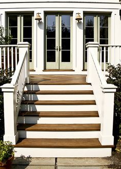 a white house with two doors and steps leading up to the front door that is open