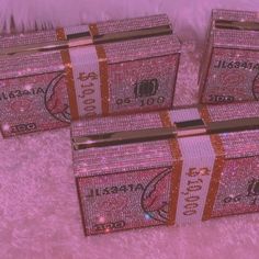 three pink boxes with gold and white designs on them sitting on top of a fur covered floor