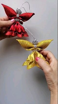 two hands are holding red and gold bows with silver beads on them, while another hand is holding a pair of scissors in the other hand