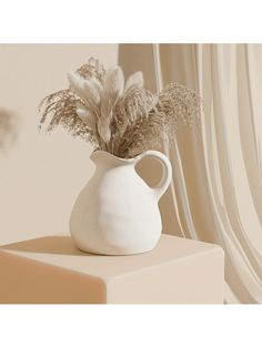 a white vase with some plants in it