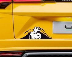 the rear end of a yellow sports car with an image of a dog on it