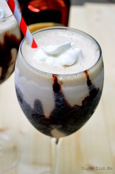 a close up of a drink in a glass with whipped cream on top and a red and white striped straw