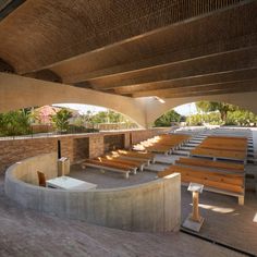 an outdoor seating area with wooden benches and brick walls on either side of the building