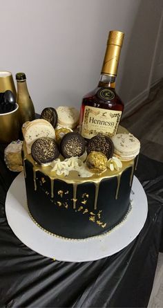 there is a cake with chocolates and liquor on the top, next to two bottles of booze