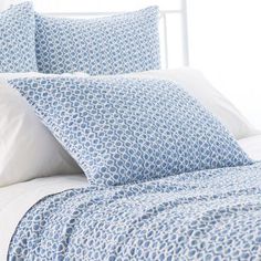 a bed with blue and white sheets and pillows