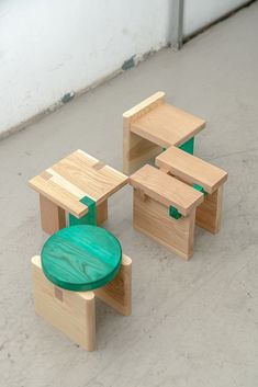 three wooden tables and two stools sitting on the floor in front of a white wall