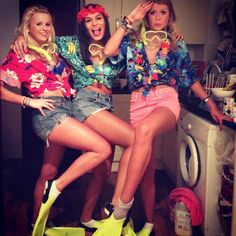 three women in colorful outfits sitting on top of a washing machine