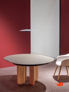 a table and chair in a room with red walls, white chairs and a lamp