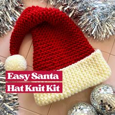 a knitted santa hat sitting on top of a table next to tinsel balls