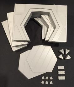 several pieces of white paper sitting next to each other on a black surface with small objects around them