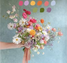 a person holding a bouquet of flowers with pink ribbon around the bottom and white daisies on top