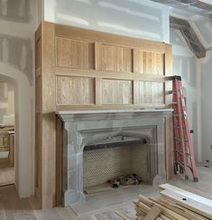 an unfinished fireplace with wood paneling being installed on the wall and around it is a ladder