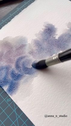 a pen is sitting on top of a piece of paper that has been drawn with watercolors