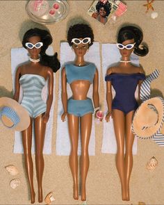 three dolls are laying on the beach towel