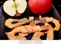 an apple and some sliced up apples on a black plate with the peels removed